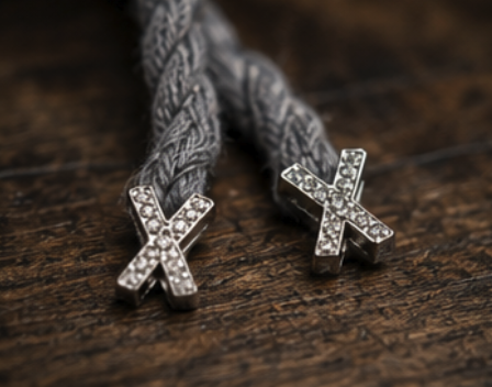 Crystal-set cross aglets on the braided rope lace, resting on aged timber