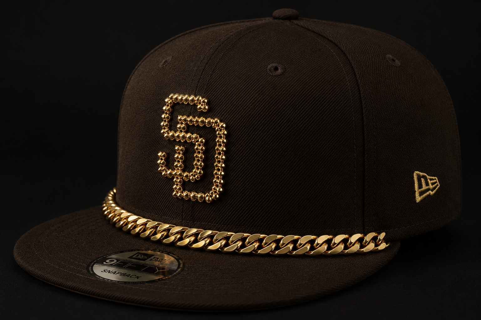 Black snapback cap with a gold beaded GP monogram and a Cuban-link gold chain sewn along the brim