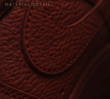 Macro of red tumbled leather grain with red on red stitching