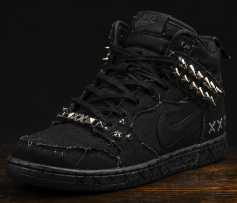 Three-quarter view of the black high-top on aged wood under low light